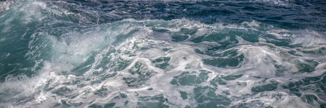 Ocean waves crashing in deep blue sea creating turbulent water surface with motion and powerful energy
