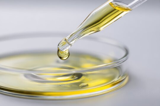 Pipette dropping yellow liquid into laboratory petri dish with chemistry research experiment laboratory analysis pharmaceutical clinical scientific solution cosmetic instrument development