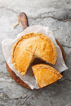 Pizza Gaina or Pizza Rustica is an Italian easter pie with mortadella, salami, mozzarella, and pecorino romano closeup on the wooden board. Vertical top view from above