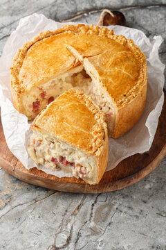 Italian savory pie pizza rustica with ricotta, mortadella, salami, mozzarella, and pecorino romano closeup on the wooden board. Vertical