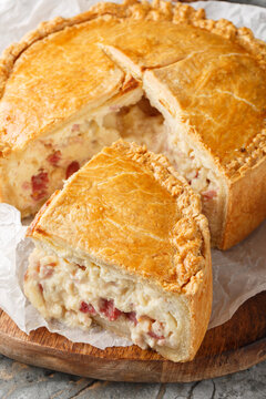Pizza Gaina or Pizza Rustica is an Italian easter pie with mortadella, salami, mozzarella, and pecorino romano closeup on the wooden board. Vertical