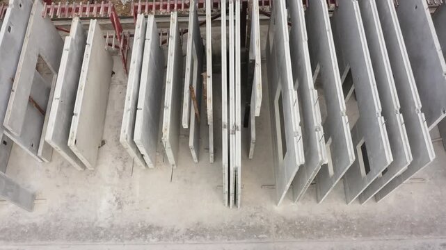 Precast Concrete Wall Panels stack securely within an industrial warehouse setting, showcasing durable gray gypsum construction materials on dark concrete floor for modern building projects.
