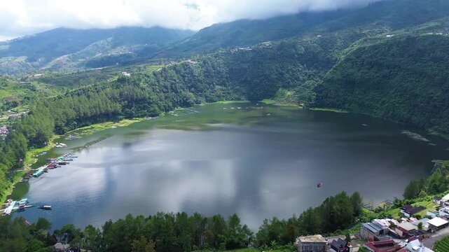 Aerial drone footage of Telaga Menjer, a beautiful volcanic lake located near the Dieng Plateau in Wonosobo, Central Java, Indonesia. Surrounded by lush green hills and spectacular mountain scenery