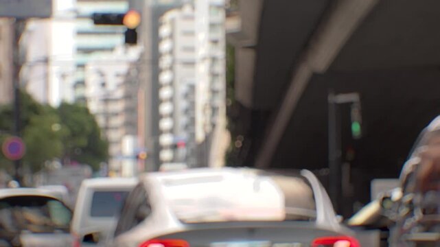 Defocused Tokyo intersection with waiting cars, moving cross traffic and pedestrians