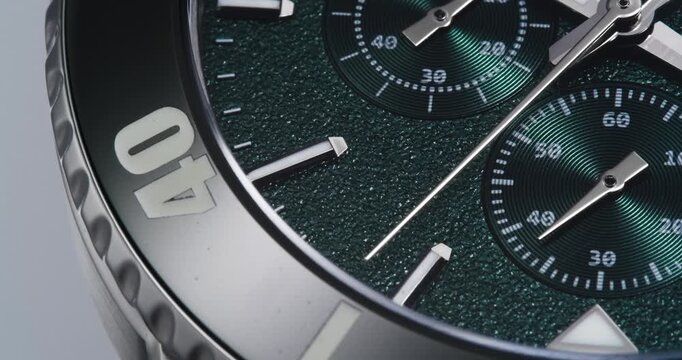 Macro close up of luxury green chronograph watch with textured dial and bezel