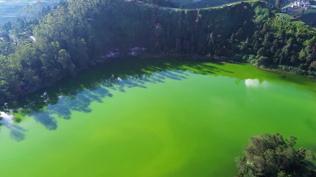 Aerial drone footage of Telaga Warna (Color Lake) on the Dieng Plateau, Central Java, Indonesia, captured during the late afternoon golden hour. 