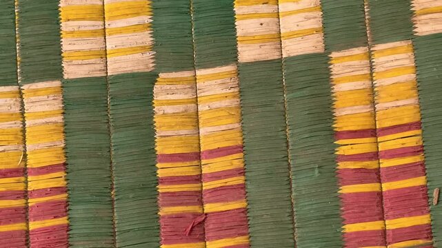Top view of a colorful handmade woven straw mat texture with striped pattern