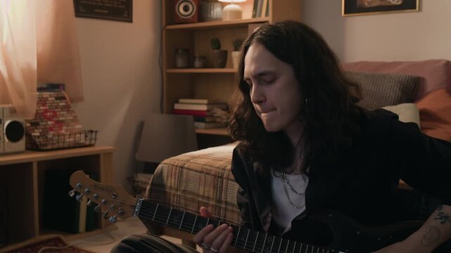 Young man with long hair using remote control, then playing electric guitar in bedroom. Footage for promoting online music lessons or creative leisure activities
