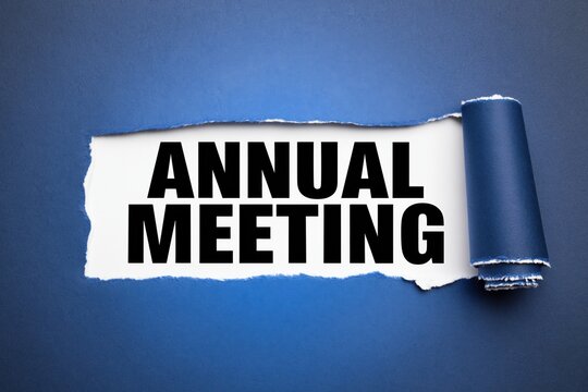 Annual meeting text written on white paper under torn blue background