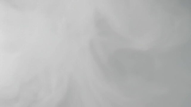 Soft white smoke swirls against a neutral gray background
