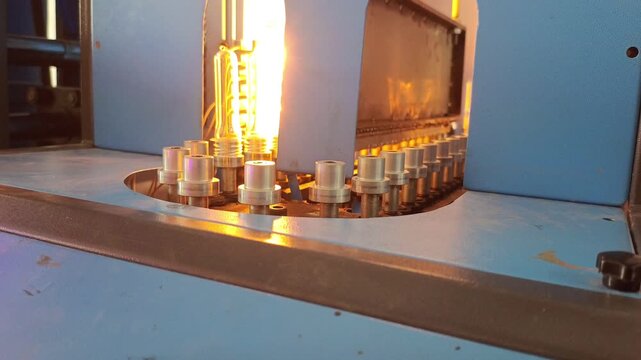 Industrial conveyor heating PET plastic preforms in a bottle molding machine
