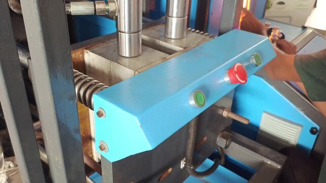 Operator working on a semi-automatic PET bottle blow molding machine in a factory
