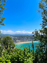 Fototapeta premium La Concha Bay panorama from Mount Urgull above sunny San Sebastian coastline and mountains, Spain