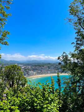 La Concha Bay panorama from Mount Urgull above sunny San Sebastian coastline and mountains, Spain