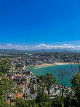 La Concha Bay panorama from Mount Urgull above sunny San Sebastian coastline and mountains, Spain