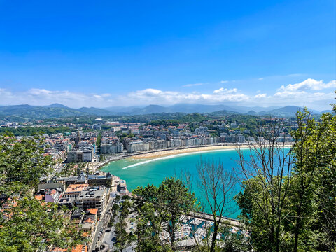 La Concha Bay panorama from Mount Urgull above sunny San Sebastian coastline and mountains, Spain