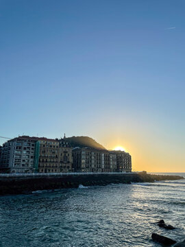 Sunset over the San Sebastian seafront with Mount Urgull, ocean waves, coastal buildings and golden hour, Spain.