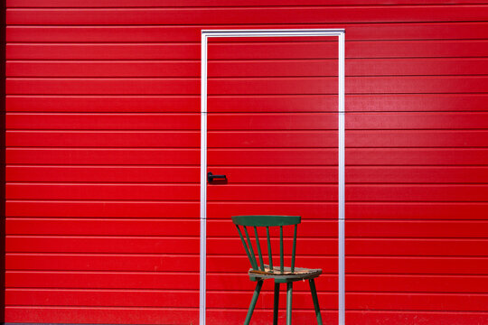 Door in a red wall with a green chair. Color contrast composition with copy space.