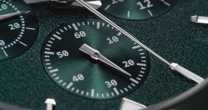 Macro close up of luxury green chronograph watch dial with ticking hands