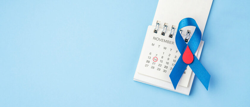 World Diabetes Day on November 14 concept. Blue ribbon with a red blood drop on a calendar over a blue background with copy space