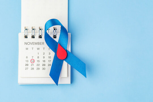 Blue ribbon with a red blood drop on a calendar over a blue background with copy space, World Diabetes Day on November 14 concept
