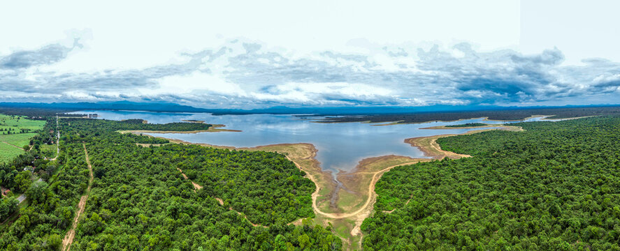 Aerial view of the expansive Udawalawe National Park reservoir surrounded by dense green forests under a cloudy sky in Sri Lanka.