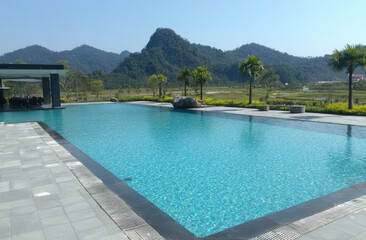 Fototapeta premium Luxury swimming pool with mountain landscape and palm trees.
