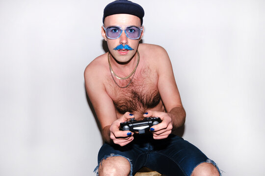 Young gay man with game controller staring against white background