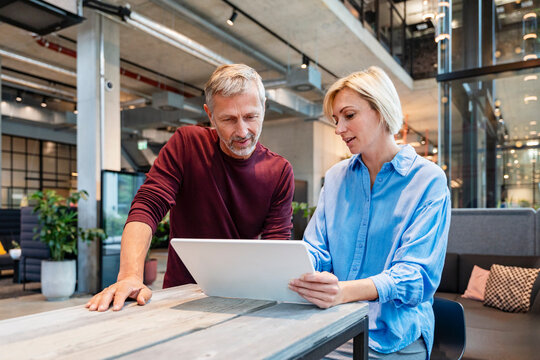 Colleagues collaborating with tablet in modern office workspace