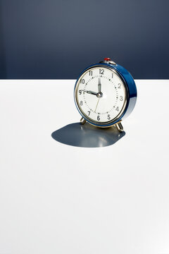 Blue retro alarm clock on white surface showing punctuality concept