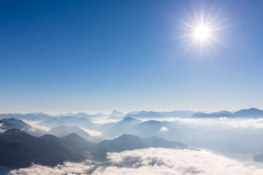 Germany, Bavaria, Summer sun shining over peaks of Bavarian Prealps shrouded in thick fog