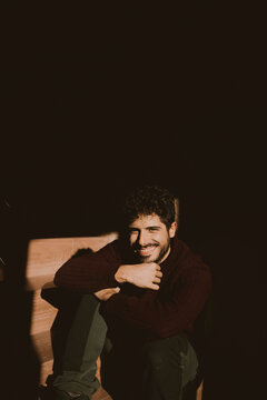 Smiling portrait of amn with dramatic shadows and warm indoor sunlight