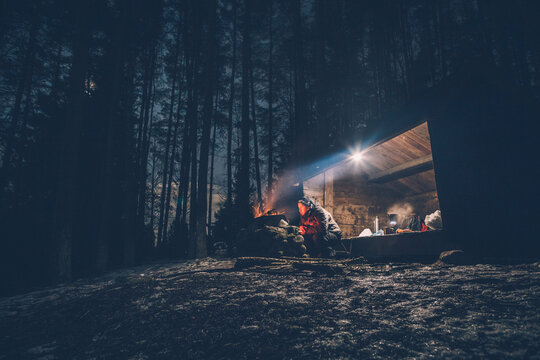 Sweden, Sodermanland, man at shelter with campfire at night