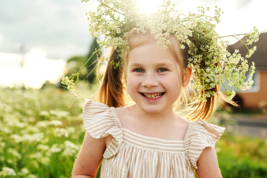 Childhood joy with floral wreath in sunny summer meadow