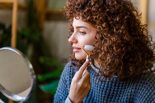 Woman using a facial roller for skincare and beauty routine at home
