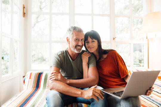 Happy couple with laptop sitting at home
