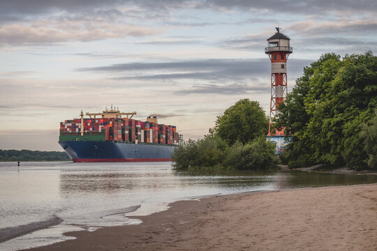 Germany, Hamburg, Container ship on Elbe river and Wittenbergen lighthouse at sunset