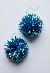 Fototapeta premium Two blue tinsel pom-poms on white background