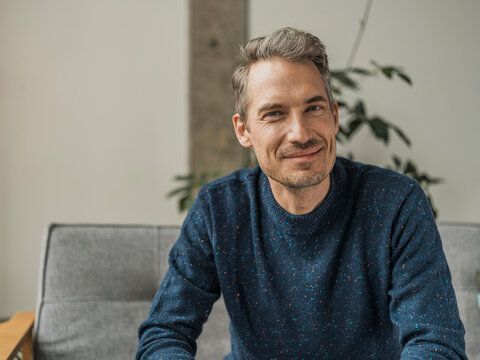 Smiling man wearing blue t-shirt sitting at home