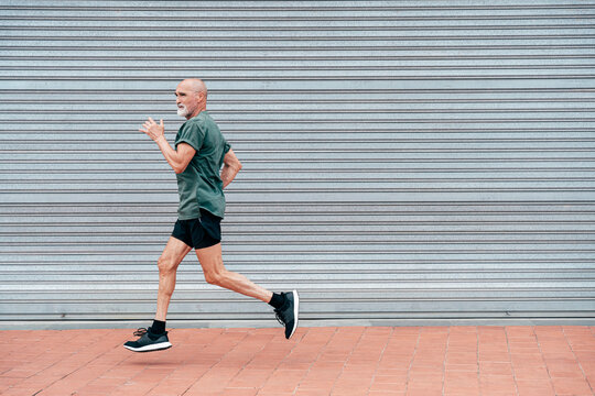 Determined active senior man running by shutter
