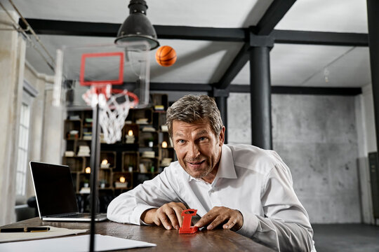Portrait of mature business man playing office games in loft