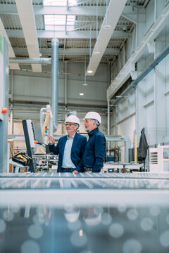 Engineers in hard hats discussing plans in a modern factory