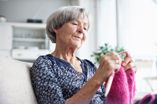 Portrait of knitting senior woman sitting on couch at home
