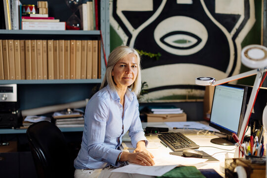 Mature woman working in architct's office, checking floor plans