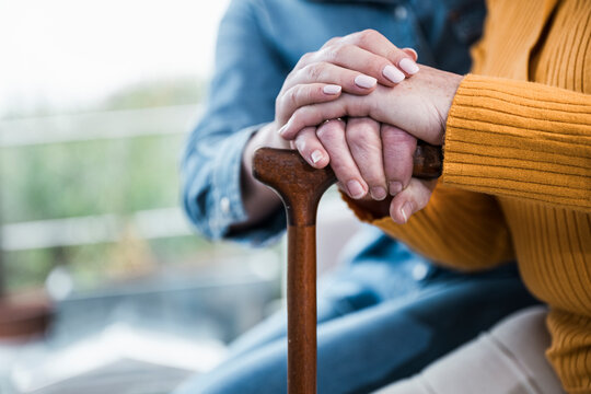 Close-up of nurse supporting patient hand on walking stick