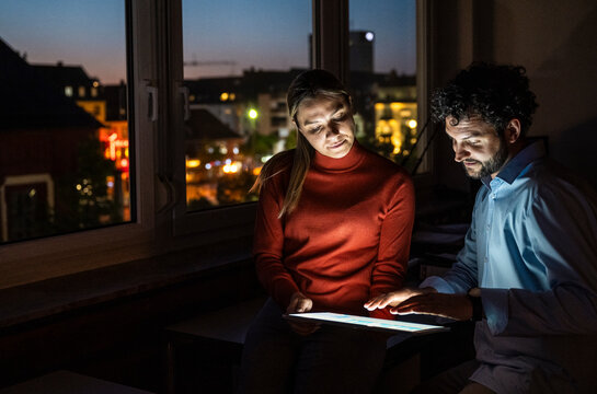Coworkers discussing business strategy on a tablet at night