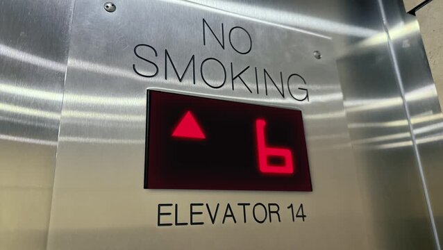 Close-up view inside a modern elevator displaying an upward arrow and floor number indicator, symbolizing vertical transportation, office buildings, and urban infrastructure. 15222