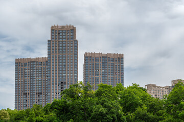 Obraz premium Modern Residential High-Rise Apartment Towers Behind Green Tree Canopies at Daytime in Shanghai, China