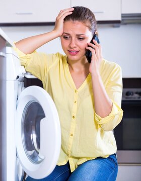 Worried woman calling handyman about washing machine malfunction