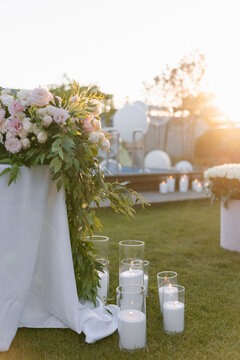 Outdoor evening party decor with flowers and candles at sunset